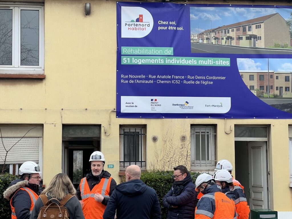 Groupe de personne devant un panneau de chantier de réhabilitation à Fort-Mardyck